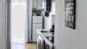 Una cocina moderna con un refrigerador de acero inoxidable, horno empotrado y pileta. Una frase motivacional se muestra en la pared.