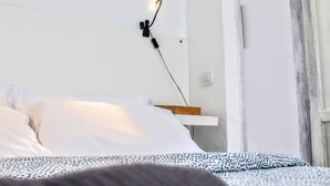 Un dormitorio con una cama, una mesita de noche, una lámpara de pared y un cuadro en la pared.