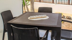 Un patio con una mesa y sillas, un paraguas grande y una piscina al fondo.
