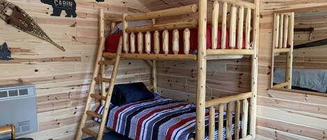 Una cama litera con una escalera, un calentador pequeño y un espejo en la pared.
