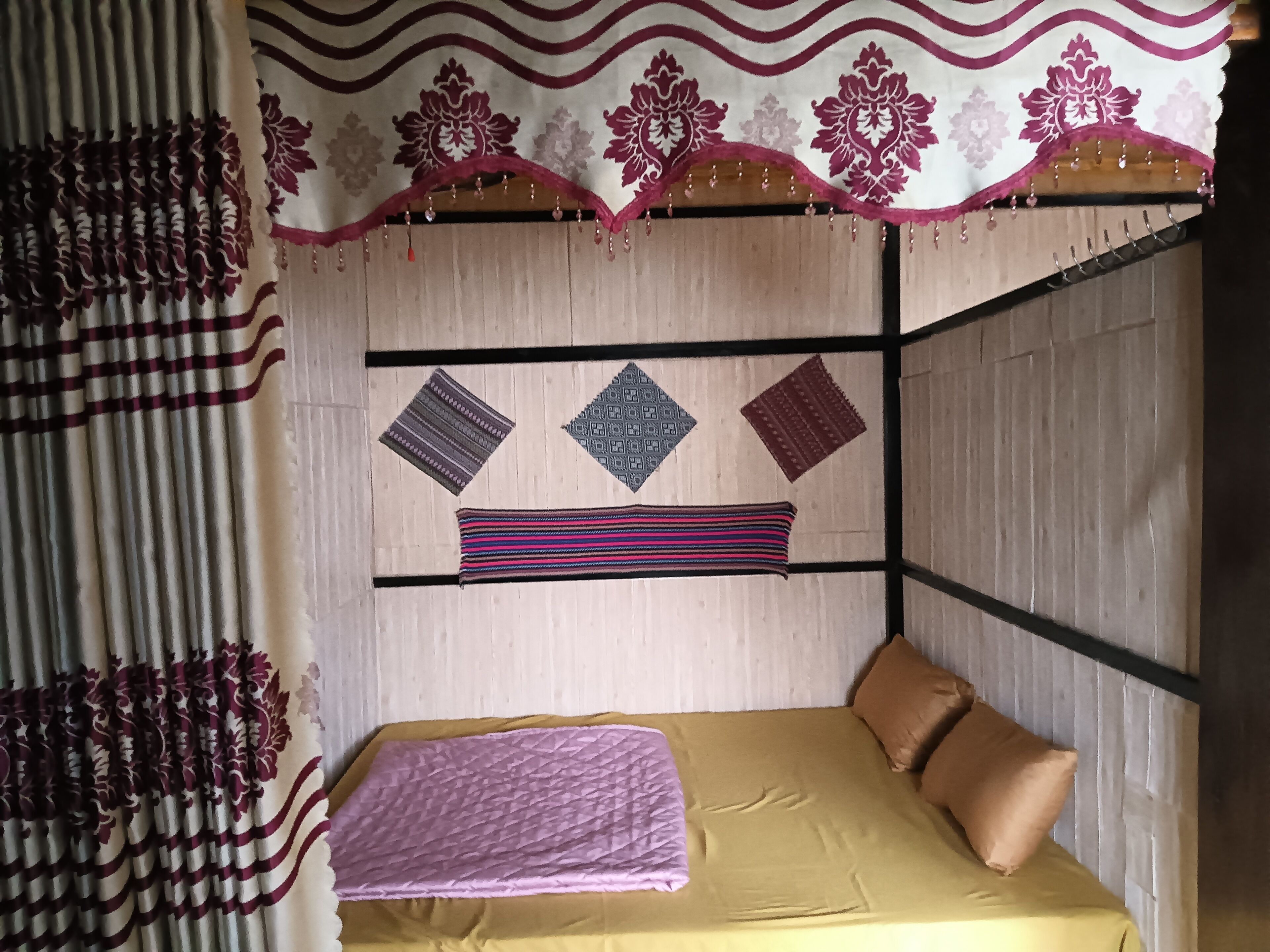 A room with a bed, a headboard, and a wall with decorative patterns and hanging items.