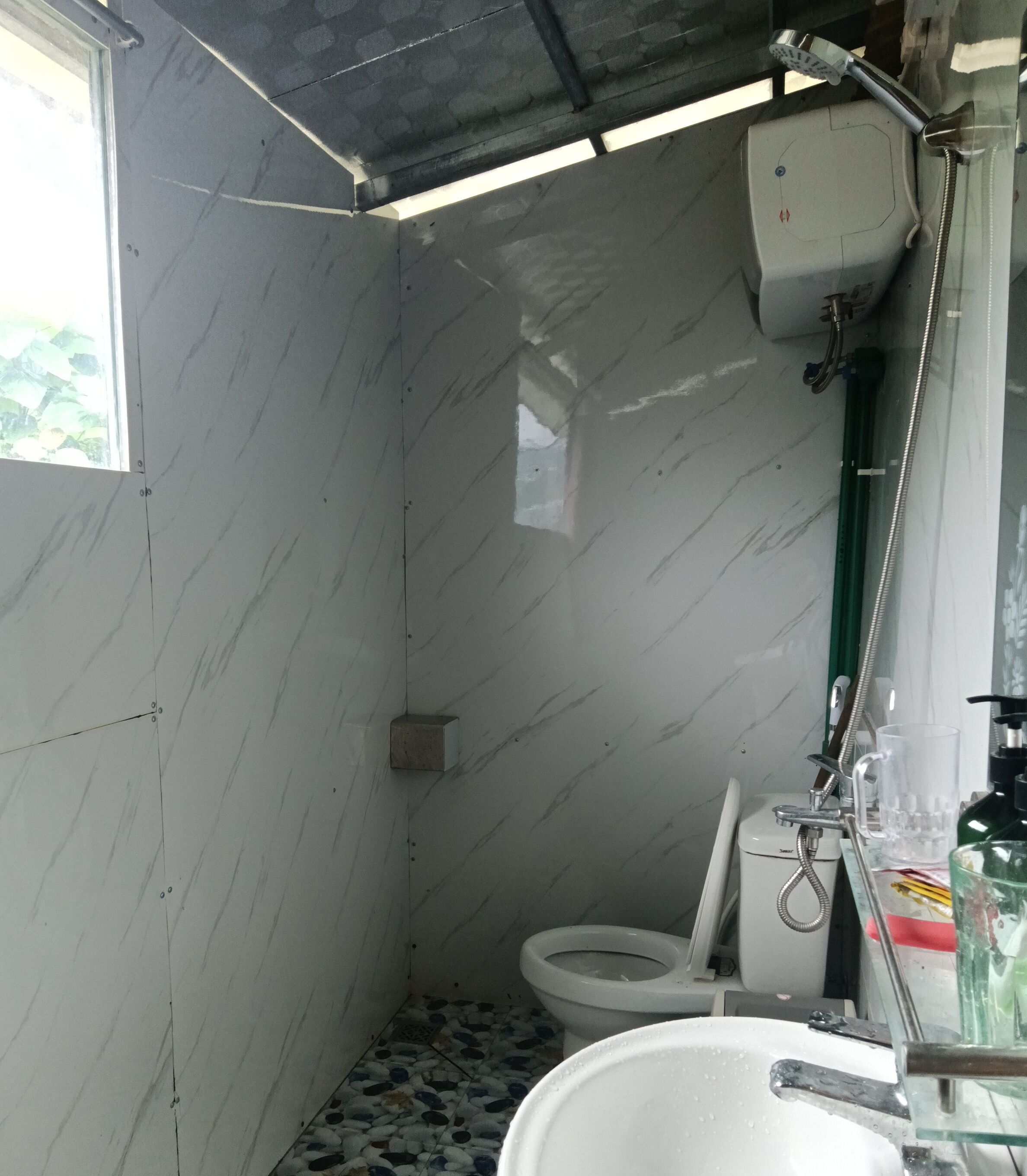 Een kleine, praktische badkamer met toilet, douche en wastafel.
