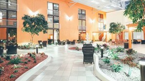 A spacious lobby with a central seating area, multiple windows, and indoor plants.