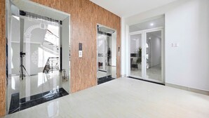 A modern hotel lobby with a polished marble floor, wooden paneling, and glass doors leading to rooms. - Cuong Anh House (Ho Chi Minh City)