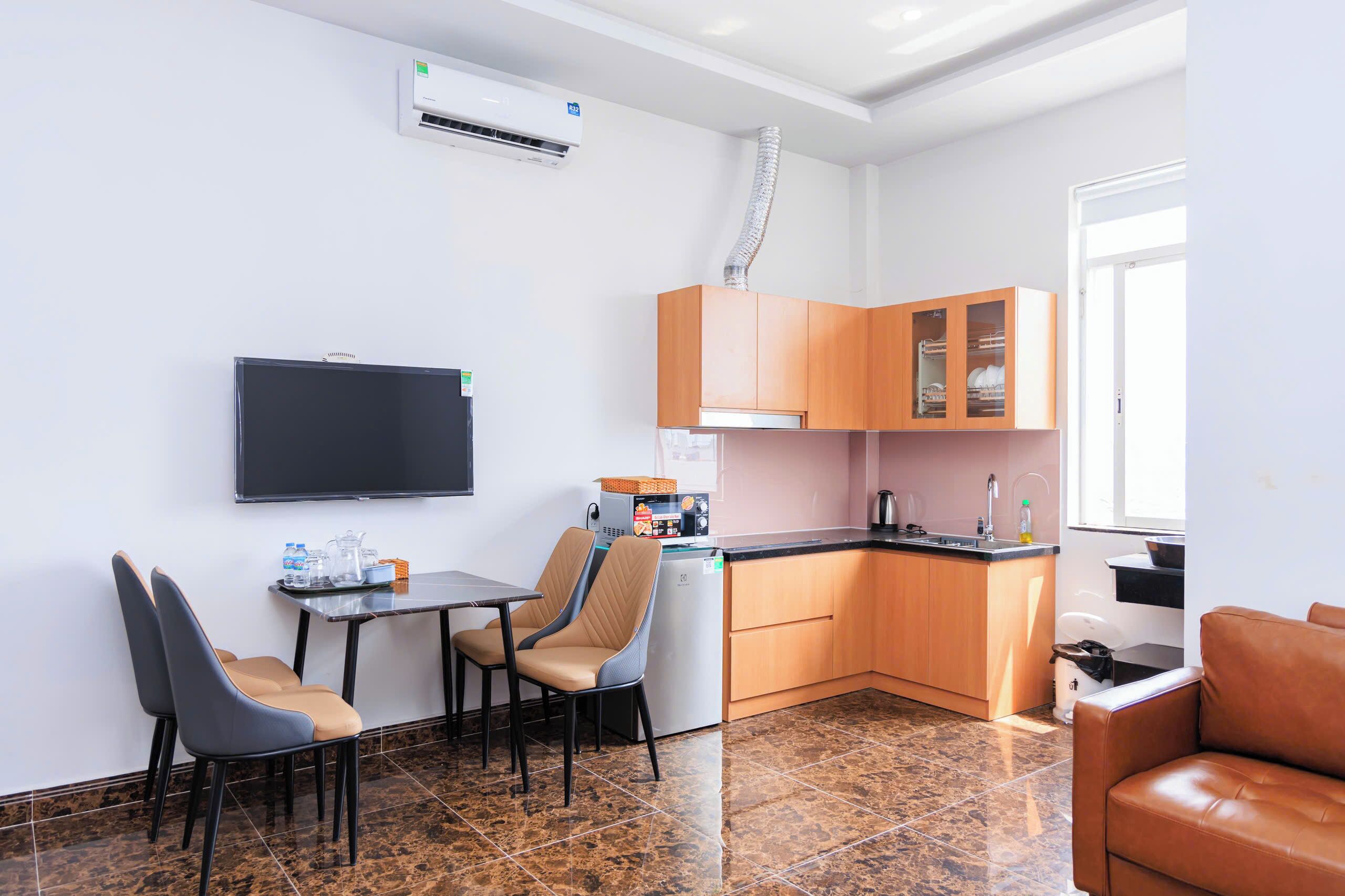 A compact kitchen with a dining area, a flat-screen TV, and a built-in oven.