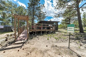 A wooden bridge leading to a cabin with a 'Welcome Guest Parking' sign. - The Barracks (Colorado Springs)