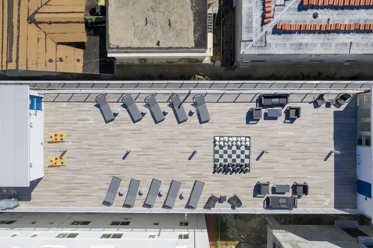 Eine Dachterrasse mit mehreren Sitzbereichen, einem Schachbrettmuster und verschiedenen Annehmlichkeiten.