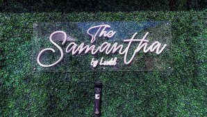 A sign with the text "The Samanthra by Looie!" against a backdrop of green foliage. - King Studio | Kitchen, Sofa Bed | Rooftop | Beach (Miami beach)