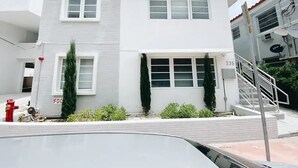 A two-story building with a white facade, multiple windows, and a visible address number.