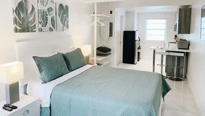 A modern bedroom with a bed, nightstands, a desk, and a ceiling fan.