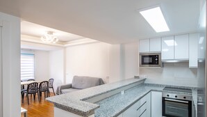 Eine moderne Küche mit integriertem Mikrowellenherd, Backofen und einer Arbeitsplatte aus Granit.