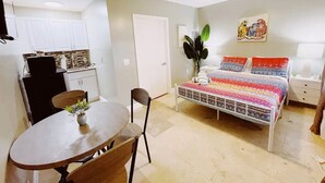 Un espacio habitable compacto con comedor, kitchenette y una cama con una colcha colorida.