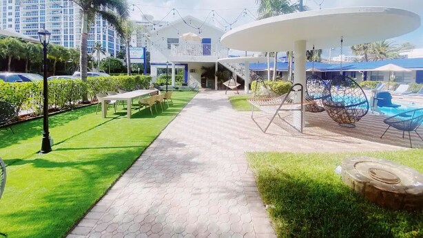 Un sendero que lleva a un edificio con piscina, zona de estar al aire libre y sillones colgantes.