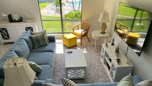 A living room with a blue sofa, a coffee table, a wicker chair, and a TV.