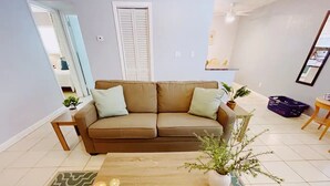 A living room with a beige sofa, a wooden coffee table, and a patterned rug. - Spacious 1 Bedroom Double Apt - Pool, Free Parking, Walk to Beach! (Lauderdale by the sea)