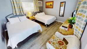 A room with two beds, a desk, a chair, a plant, and a painting on the wall. - Cozy Standard Double Room - Steps to Beach, Free Parking & Pool (Lauderdale by the sea)