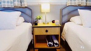 A hotel room with two beds, a bedside table with a lamp, a clock, and a small potted plant. - Cozy Standard Double Room - Steps to Beach, Free Parking & Pool (Lauderdale by the sea)