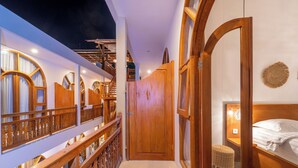 Une chambre d’hôtel avec un balcon en bois, une grande porte en bois et un lit doté d’une tête de lit.