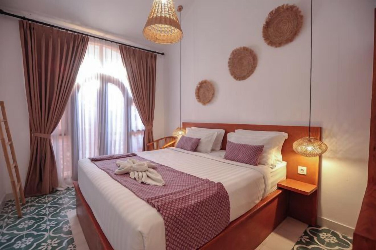 A neatly made bed with a red and white bedspread, a wooden headboard, and a bedside lamp.