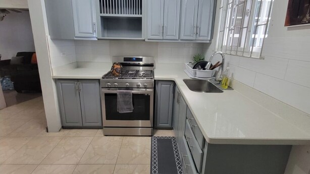 A compact kitchen with grey cabinets, a stainless steel stove, and a sink.