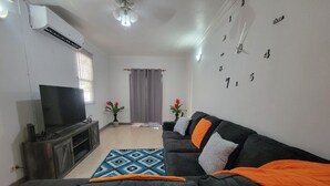 A living room with a TV, sofa, and decorative pillows.