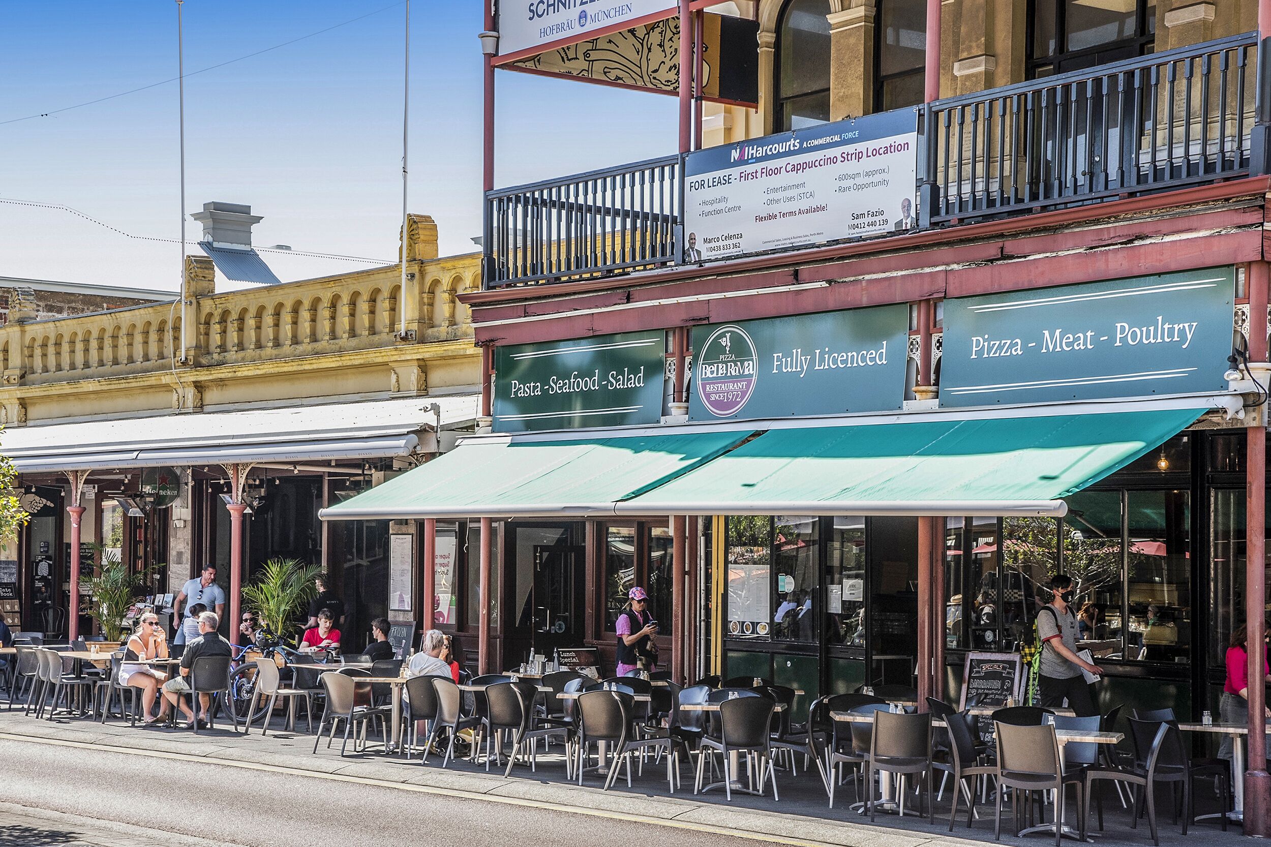 A restaurant with outdoor seating, a sign for 'Pasta - Seafood - Salad', and a 'Fully Licensed' sign.