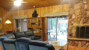 Ein gemütliches Blockhaus-Interieur mit Kamin aus Stein, Holzbalkendecke und einer großen Eckcouch.