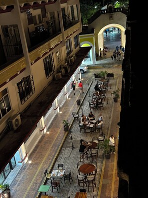 Un patio con mobiliario exterior, un corredor cubierto y vista a la calle.
