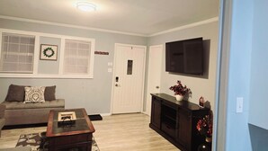 Una sala de estar con sofá, mesa de centro, chimenea, televisor y una puerta decorada con un adorno.