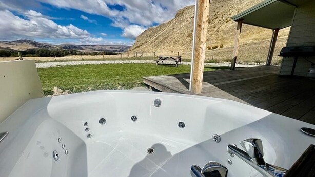 Un bain à remous avec une terrasse en bois et une vue sur un paysage montagneux.