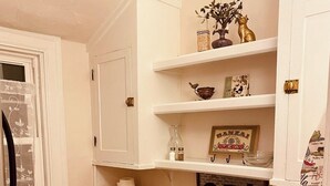 A compact kitchen with white cabinets, a wooden countertop, and a sink. There are shelves above the countertop holding various items, including a framed picture and a vase. - Morocco Loft 2BR overlooking city walking mall  (Winchester)