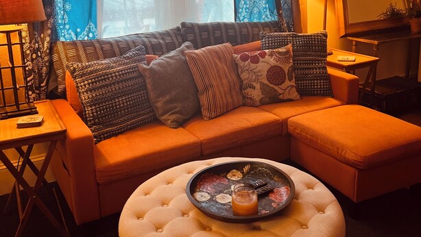 A living room with a sofa, ottoman, lamp, and a mirror. - Morocco Loft 2BR overlooking city walking mall  (Winchester)