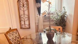 A dining area with a glass table surrounded by patterned chairs, a potted plant, and a decorative metal piece on the wall. - Morocco Loft 2BR overlooking city walking mall  (Winchester)
