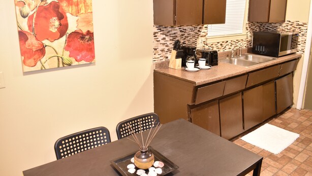 A compact kitchen with a microwave, sink, and a dining area with chairs. - Cute 3br Ranch, Home Away From Home, Sleeps 6 (Detroit)