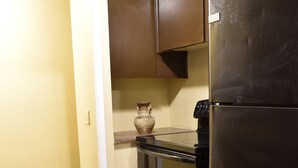 A kitchen with a refrigerator, oven, and a door leading to another room. - Cute 3br Ranch, Home Away From Home, Sleeps 6 (Detroit)