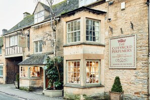 Un edificio de piedra tradicional con un letrero que indica que es una tienda llamada 'The Cotswold Perfumery'.