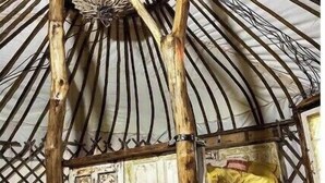 Eine traditionelle Jurte mit Holzrahmen und einer runden Öffnung im oberen Bereich.