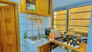 Une cuisine compacte équipée d’un four à micro-ondes, d’une cuisinière et de divers ustensiles.