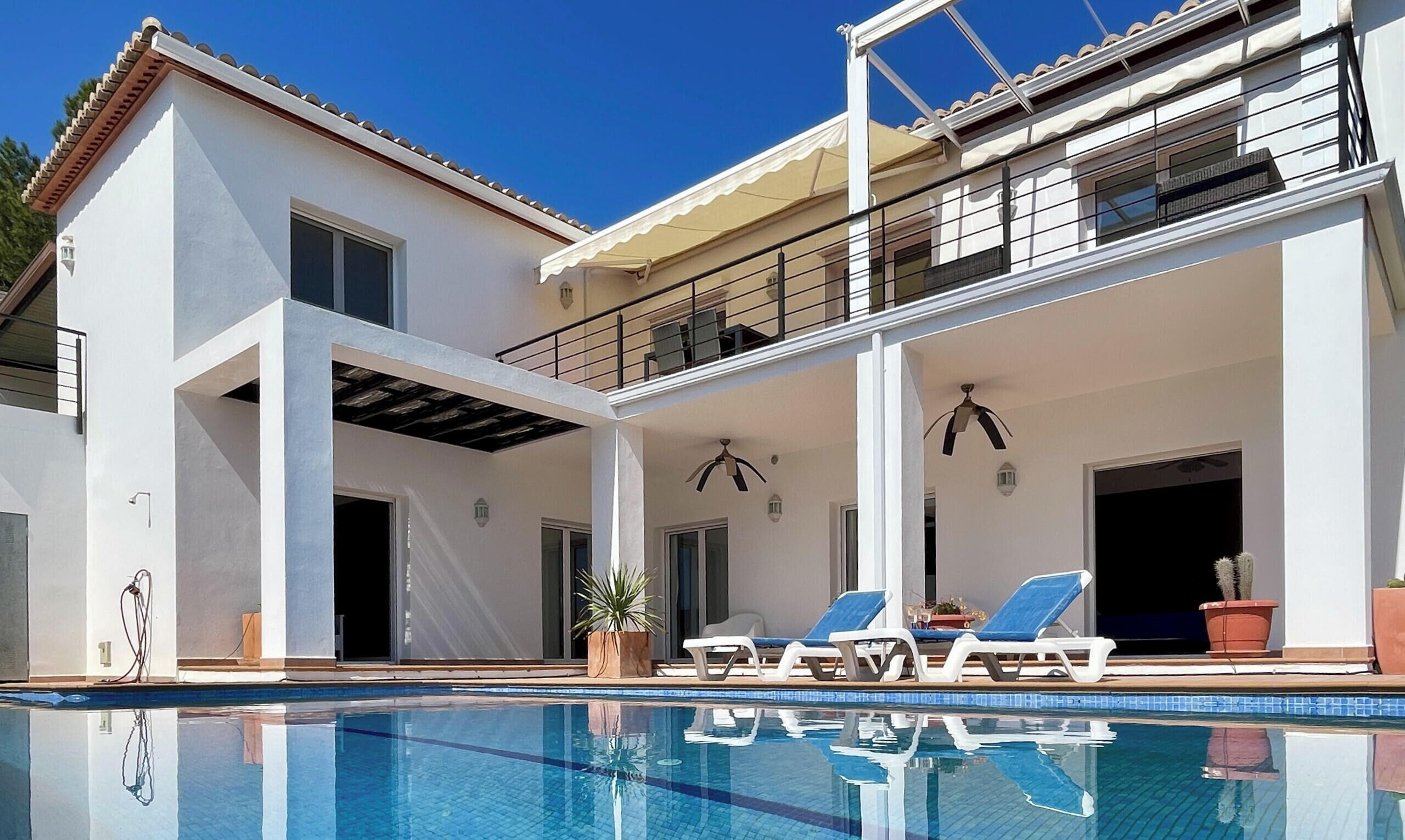 Ein zweistöckiges Haus mit Schwimmbad, Außenbereich und überdachter Terrasse.