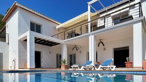 Ein zweistöckiges Haus mit Schwimmbad, Außenbereich und überdachter Terrasse.