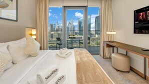 A hotel room with a large bed, a desk, a chair, and a view of the city skyline. - NEW | 2BR Burj NYE Fireworks View | Dubai Mall (Dubai)