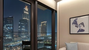 A modern living room with a large balcony overlooking a cityscape at night. - NEW | 2BR Burj NYE Fireworks View | Dubai Mall (Dubai)
