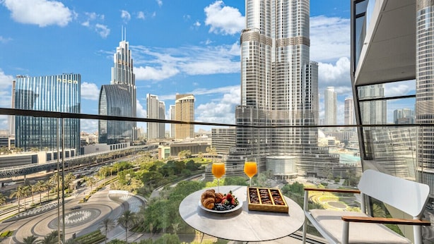 A balcony with a table set for breakfast, overlooking a cityscape with modern skyscrapers. - NEW | 2BR Burj NYE Fireworks View | Dubai Mall (Dubai)