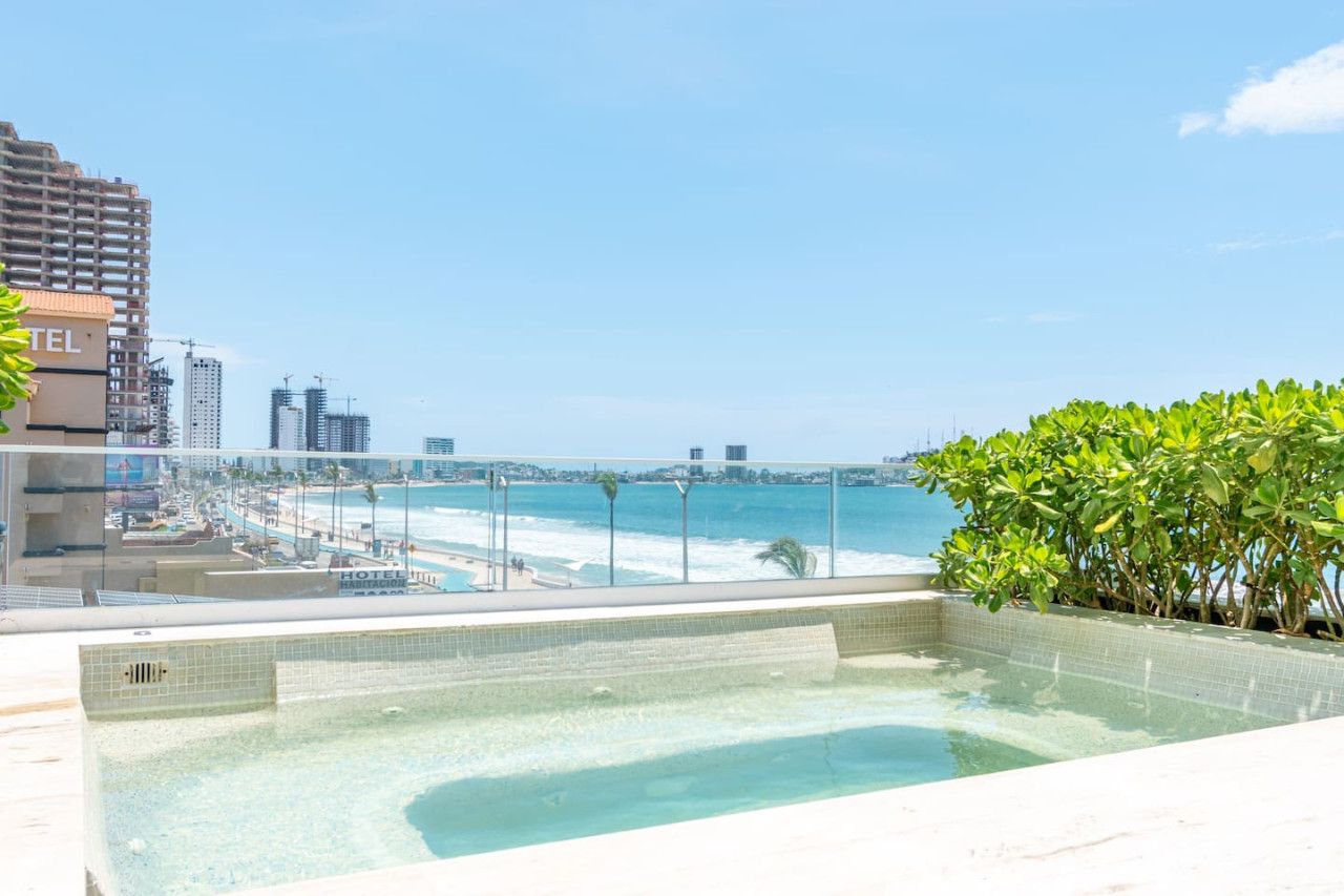 Una piscina en la azotea con vistas a la playa y al horizonte de la ciudad.