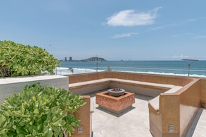 Una terraza en la azotea con zona de estar, una chimenea y vista al océano.
