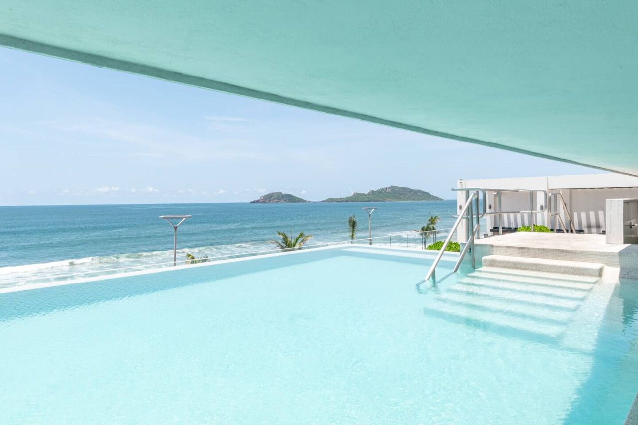 An infinity pool with a view of the ocean and a small island.