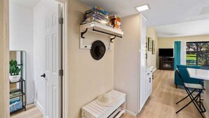 A compact kitchen with a white countertop, a small bench, and a wall-mounted shelf with books. - Golf Resort 2BR | Pool, Spa & Pickleball (Palm Desert)