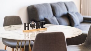 En moderne stue med et rundt marmorbord, grå sofaer og et skilt med teksten 'HOME' samt en globe.