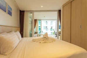 A hotel room with a large bed, a wooden wardrobe, and a view of the outside balcony.