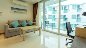 A modern living room with a sofa, coffee table, and a view of a balcony with outdoor furniture. - Sea View Beach Dinning Beach Front c115 (Rawai)